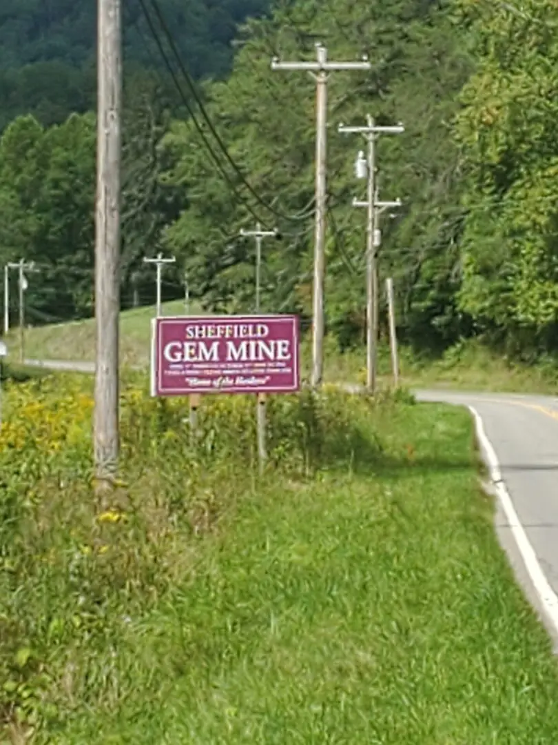 A sign on the side of a road that says sheffield gem mine.
