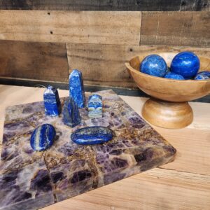 A bowl of blue stones and a wooden board with rocks on it.