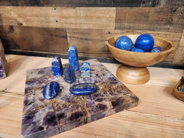 A bowl of blue stones and a wooden board with rocks on it.