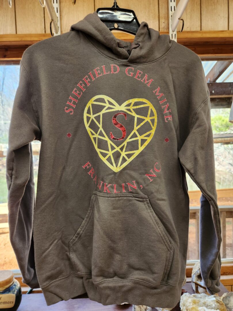 A brown hoodie with a gold heart on it.
