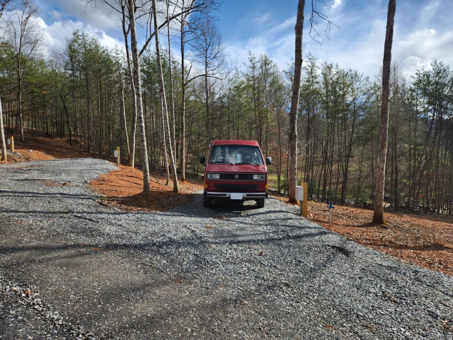 A van parked on the side of a road in the woods.