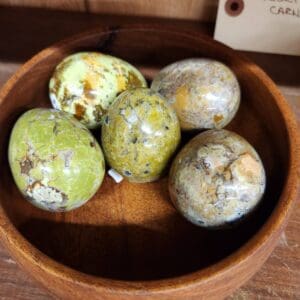 A wooden bowl with some green apples in it