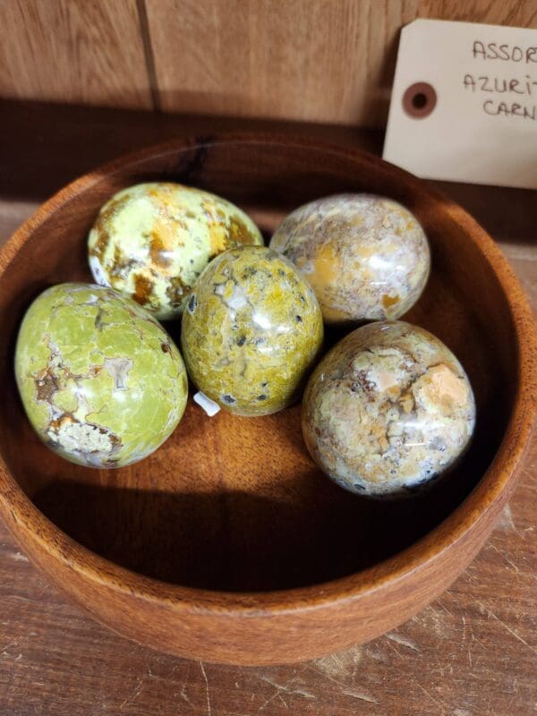 A wooden bowl with some green apples in it