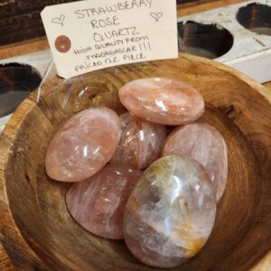 A wooden bowl with some pink stones in it