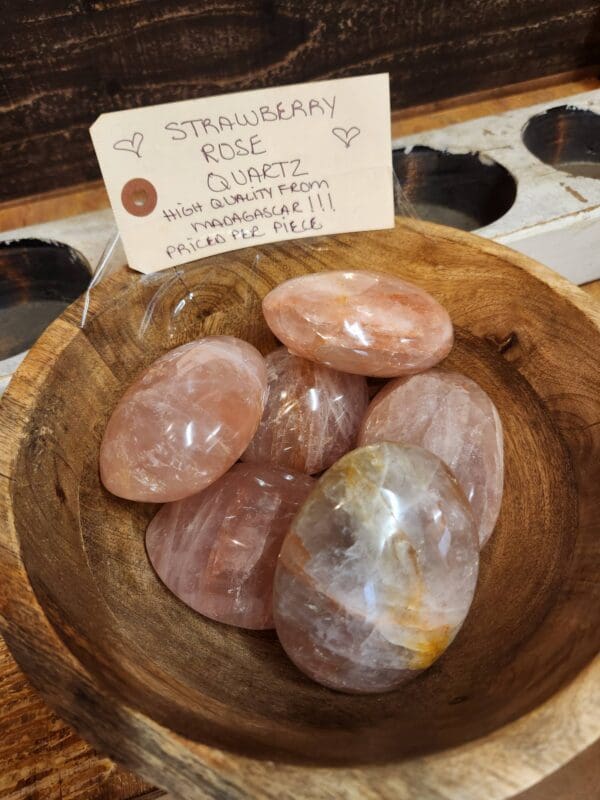 A wooden bowl with some pink stones in it