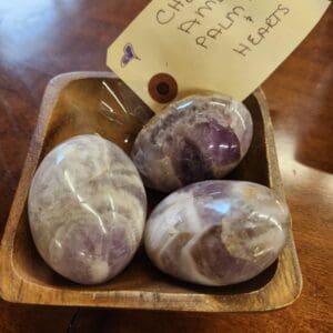 A wooden bowl with three purple and white stones.