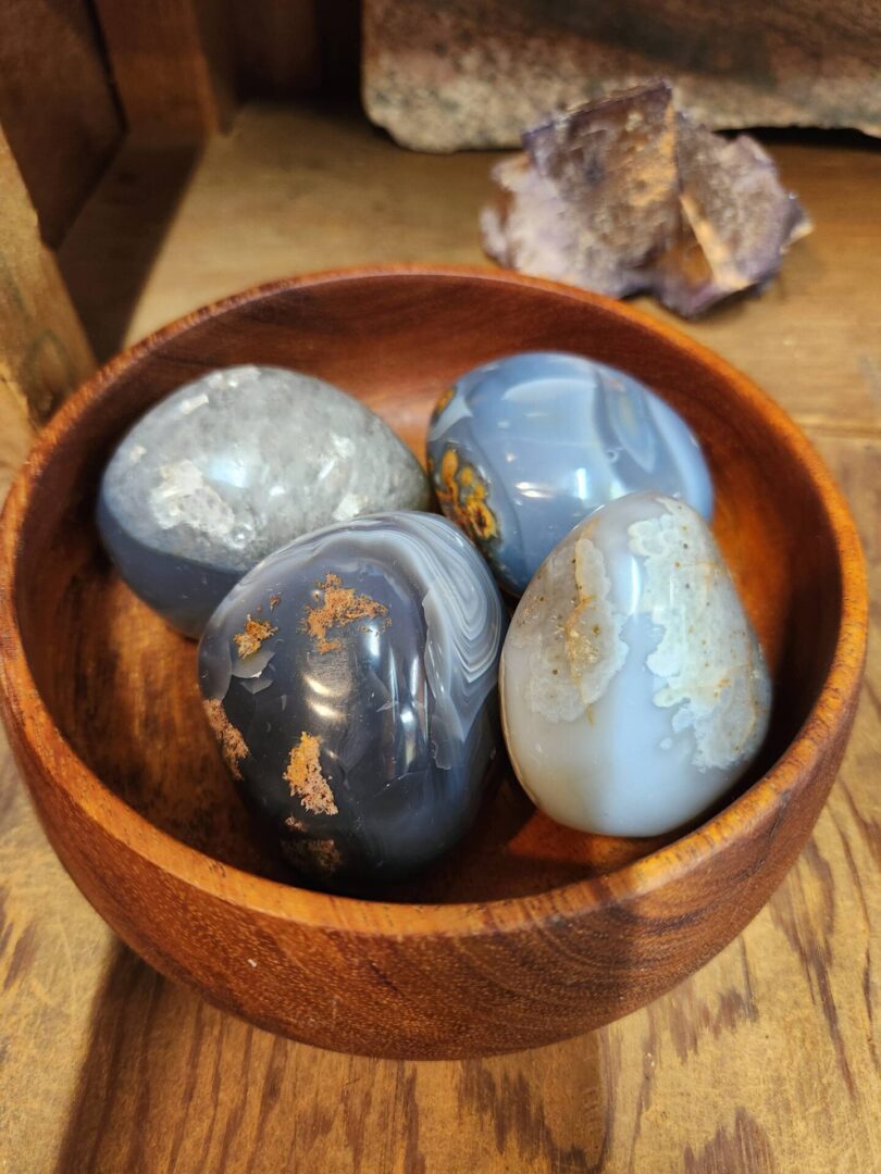 A wooden bowl with some blue and white rocks in it
