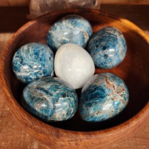 A bowl of blue and white stones with one egg in it.