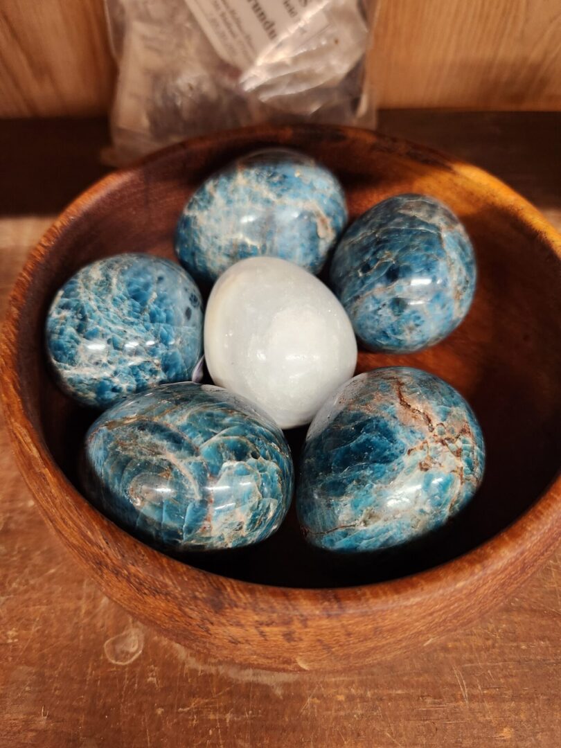 A bowl of blue and white stones with one egg in it.