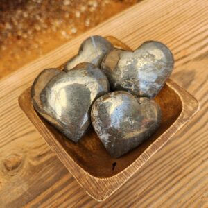 A wooden bowl with four metal hearts in it.