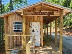 Wooden cabin with a porch and sign.